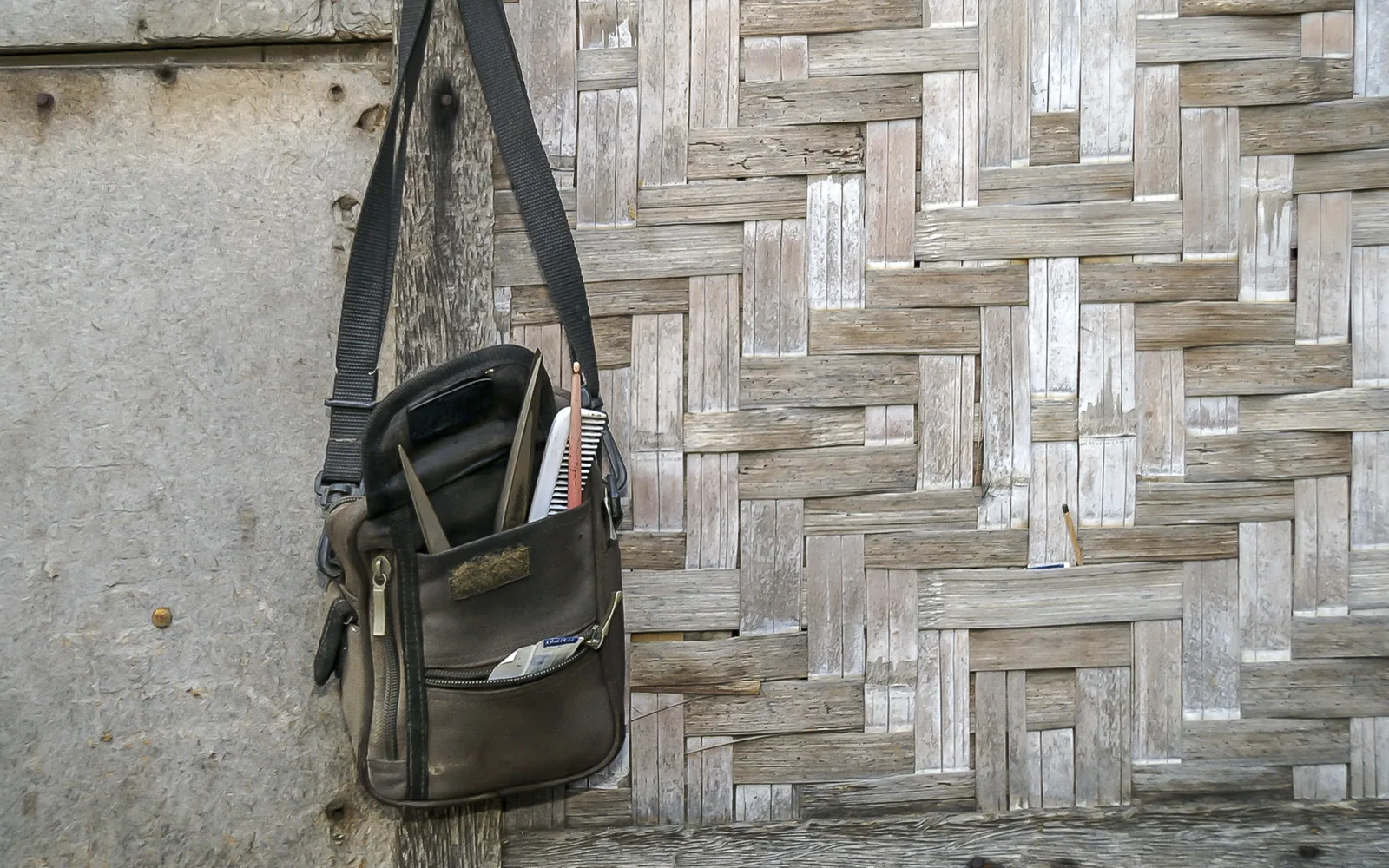 A hairdresser's bag with scissors and combs, hanging on a woven bamboo wall in Cebu City